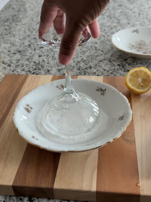 Rimming a martini glass with sugar.